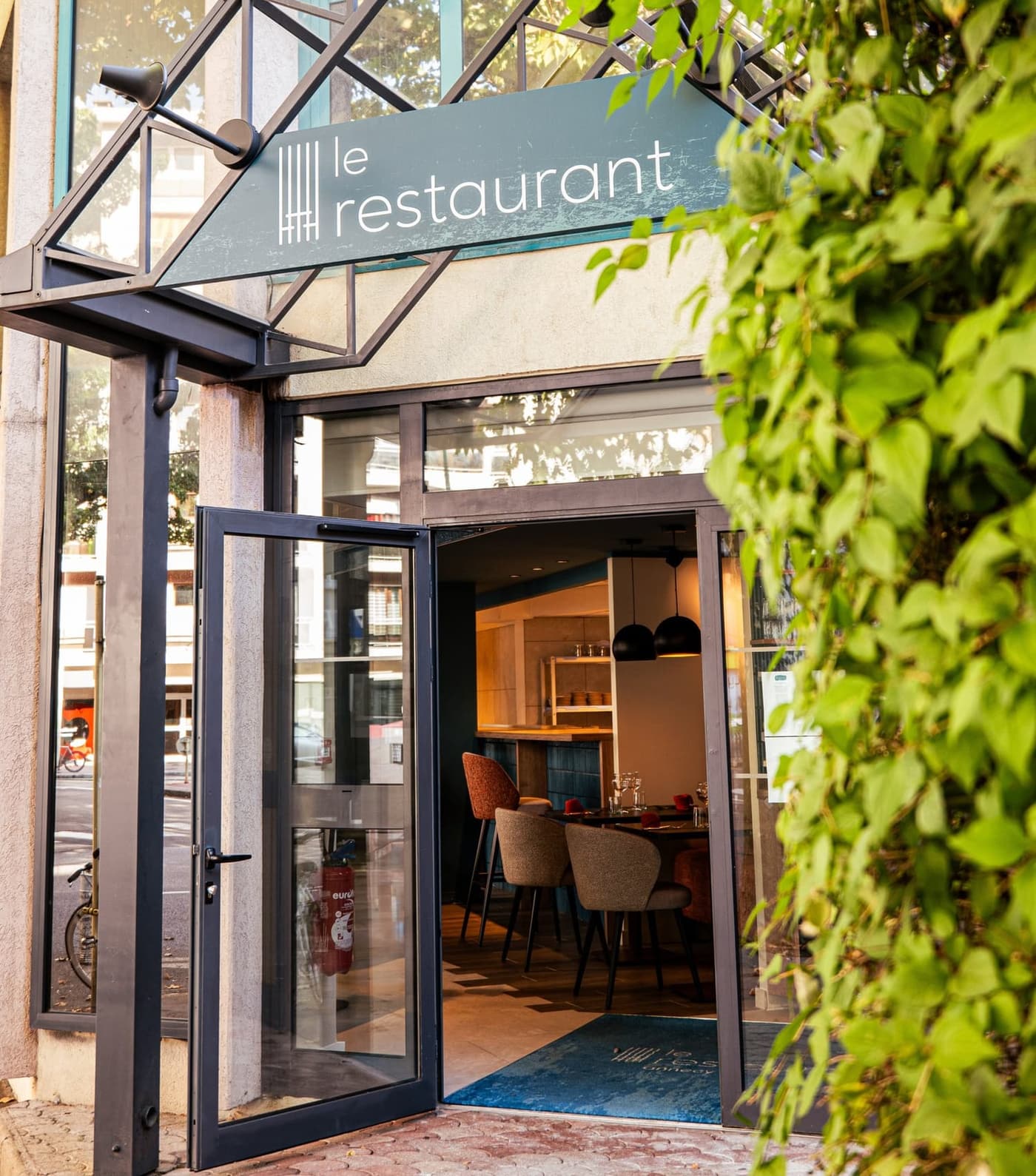 La devanture du restaurant le soir, enseigne « le restaurant » et façade vitrée