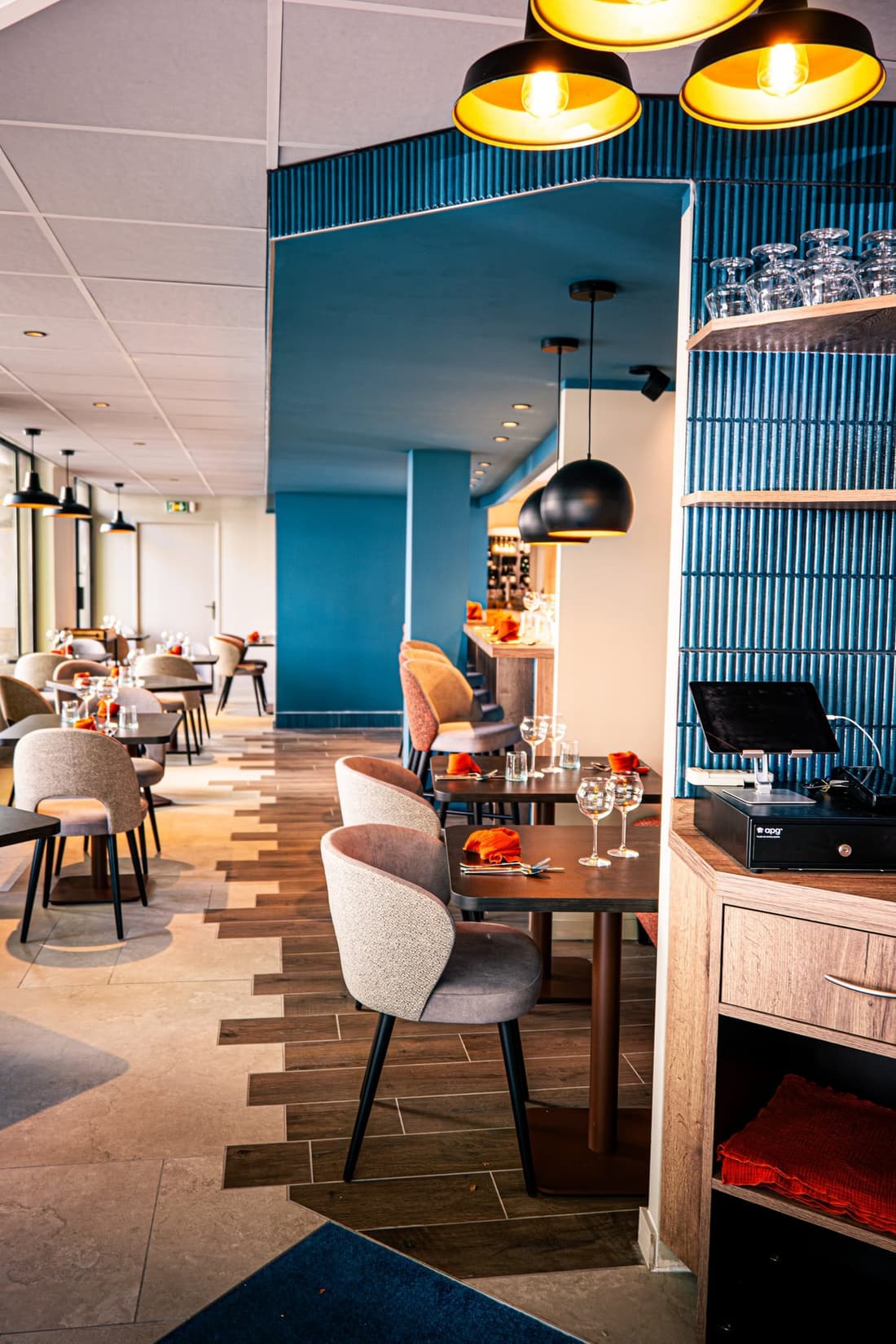 La salle du restaurant, tables dressées et mur bleu profond